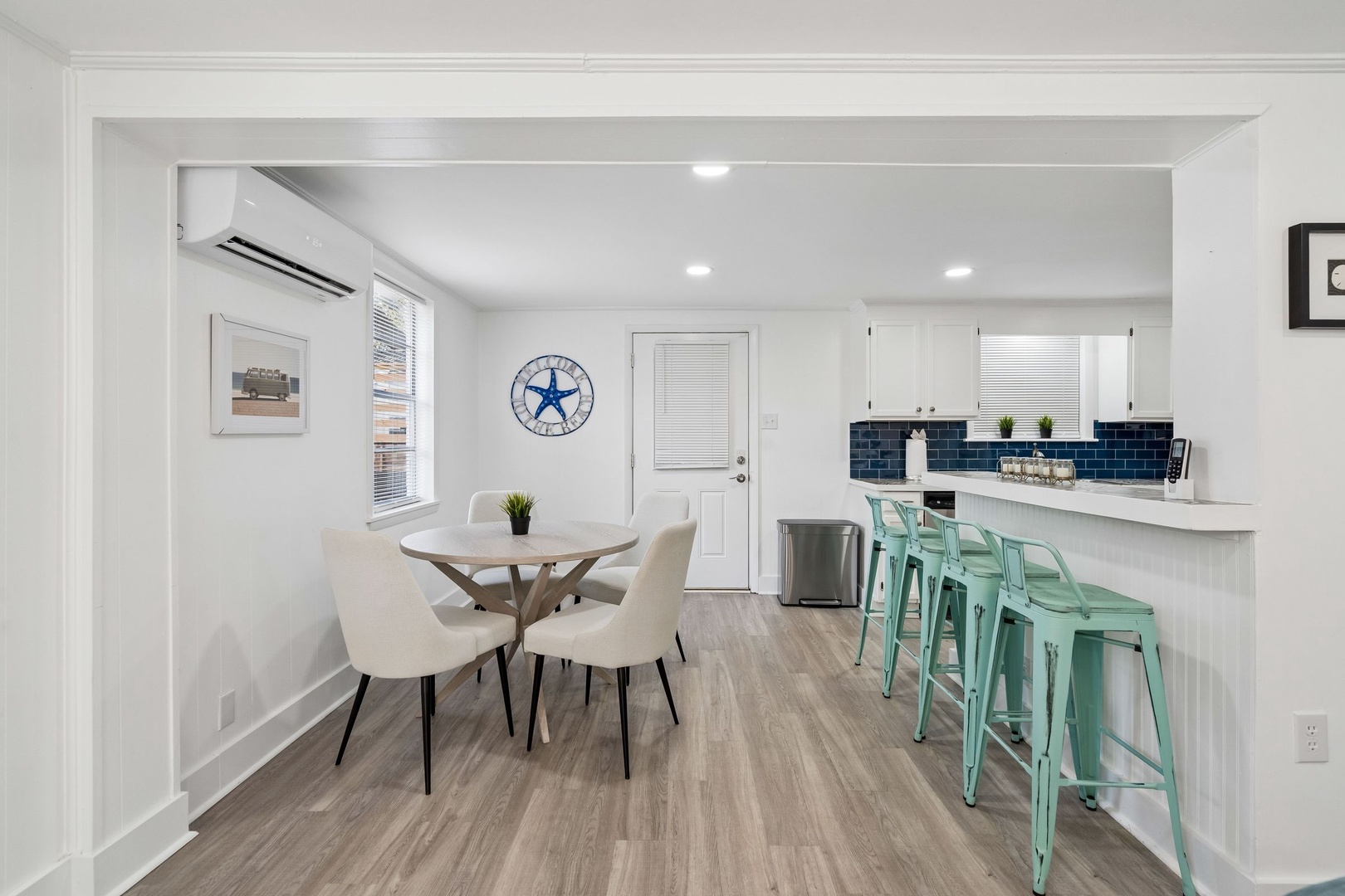 Your bright, modern dining space flows seamlessly into the fully equipped kitchen with stylish mint bar stools and fresh coastal charm.