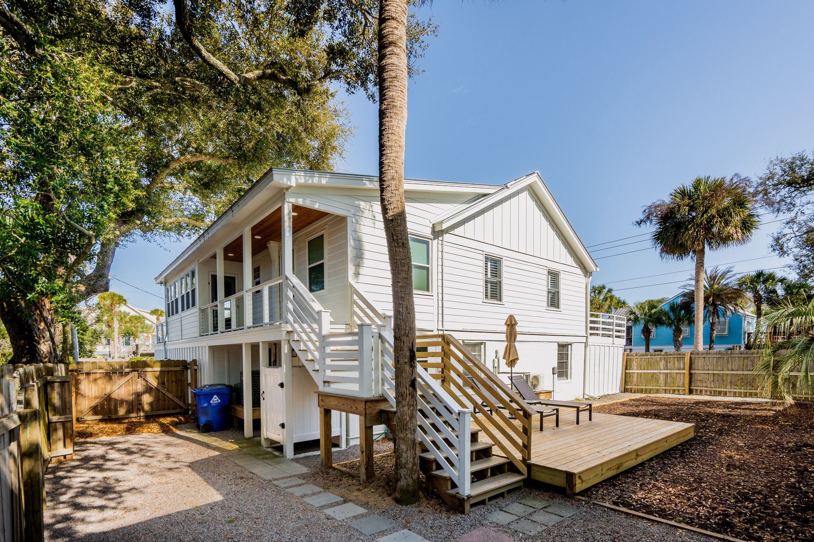 Charming coastal cottage with elevated design and tropical palm trees creating the perfect island retreat atmosphere.
