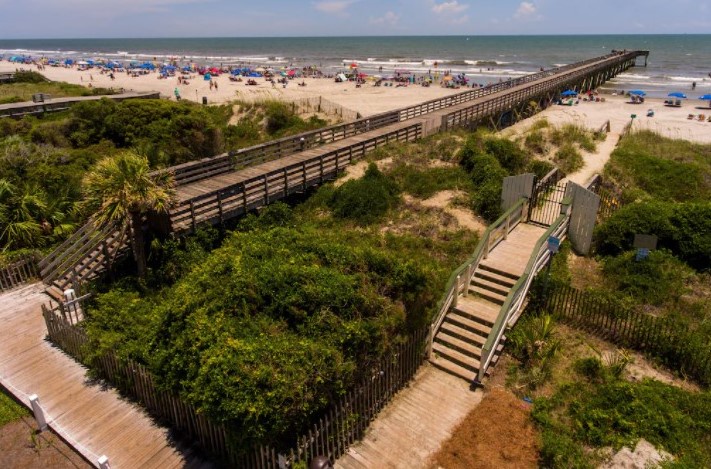 Scenic beach access with wooden boardwalk leading to pristine sandy shores and ocean views.