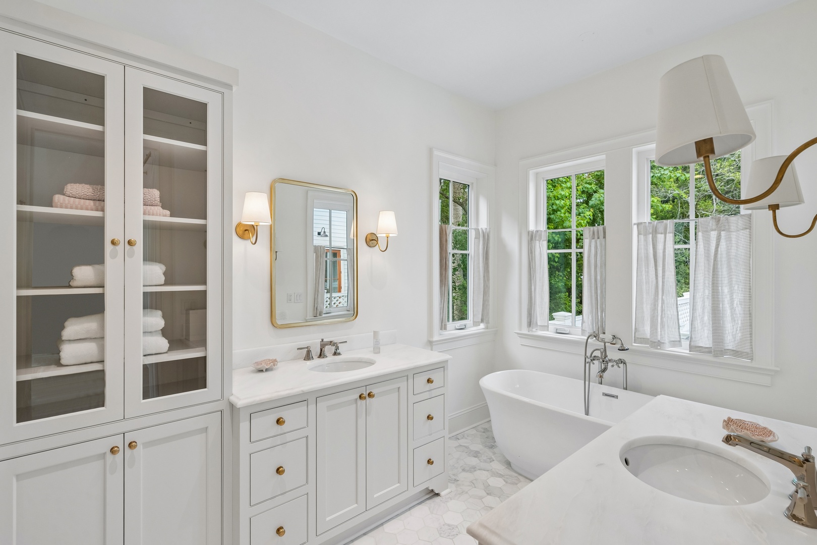Your serene bathroom retreat features a luxurious soaking tub and elegant fixtures, all bathed in natural light. Crisp white finishes and thoughtful storage details create a peaceful atmosphere where you can unwind.