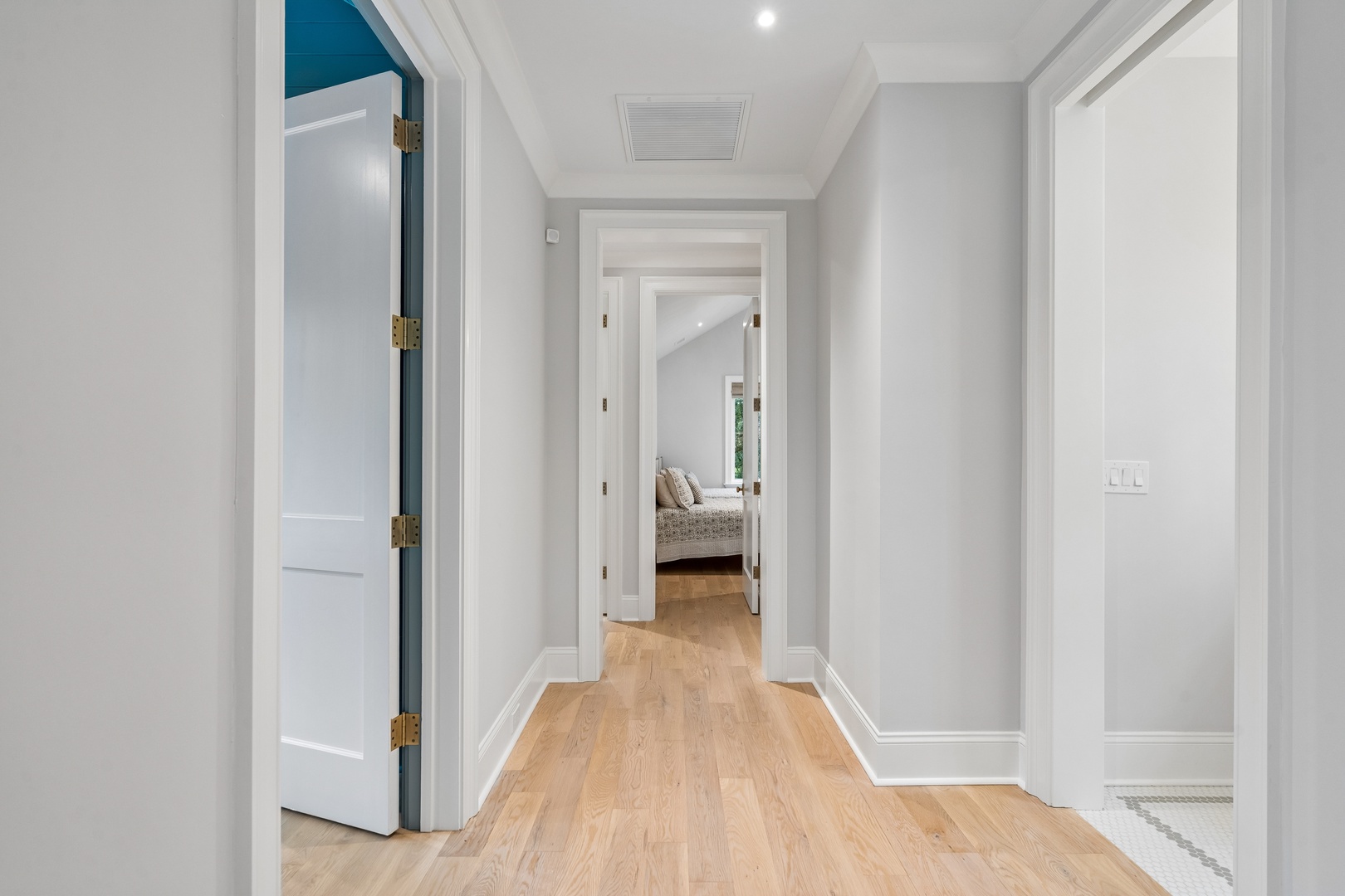 Bright, welcoming hallway with gleaming hardwood floors and fresh white trim leads you to your peaceful bedroom retreat just ahead.