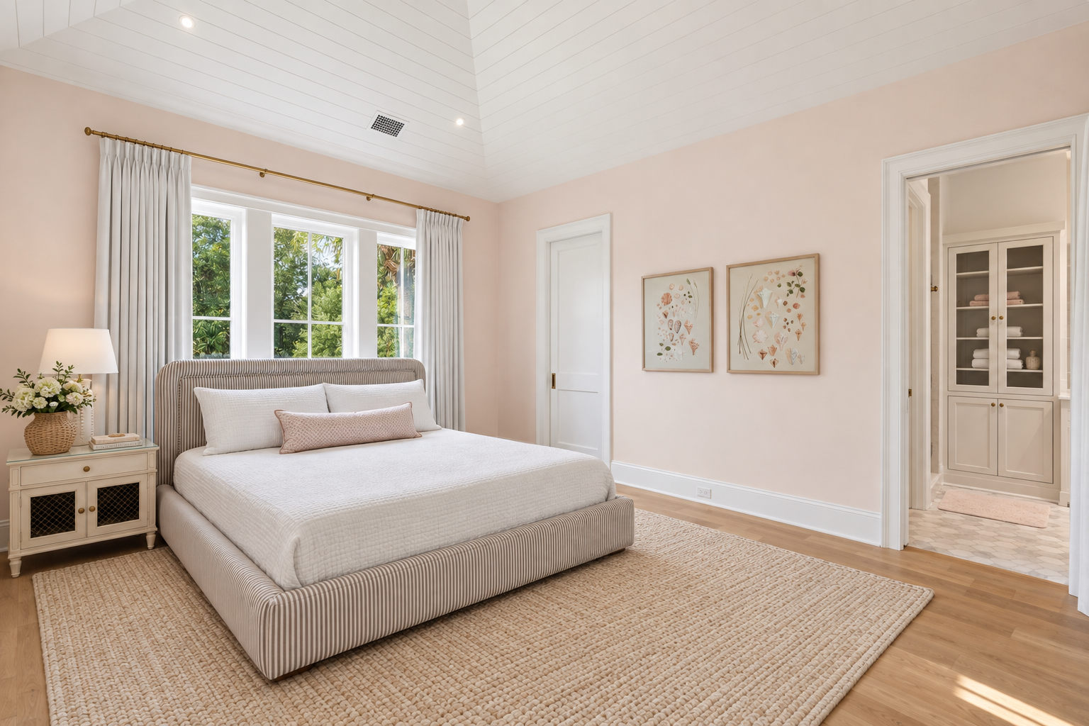 Sink into the plush bed and let natural light from the expansive windows warm your serene retreat. Soft blush walls and elegant botanical prints create a calming, inviting atmosphere for your perfect escape.