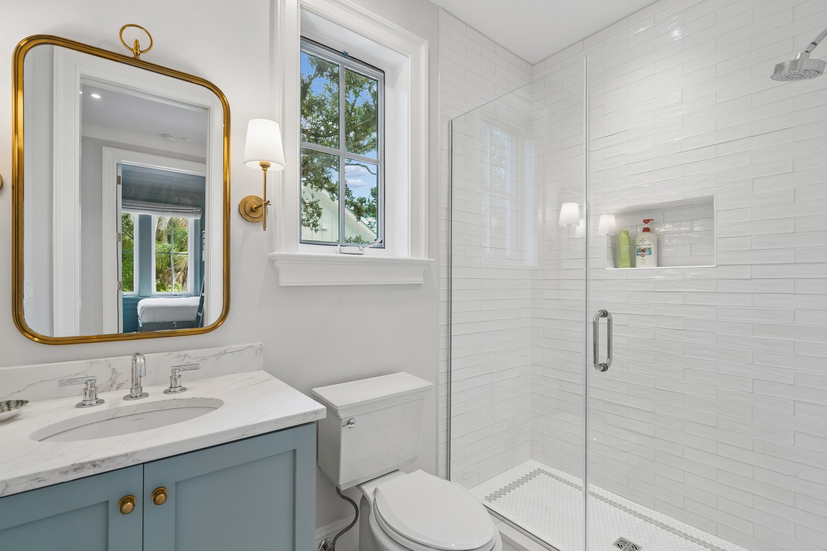 Step into your bright, elegant bathroom with pristine white subway tile, a walk-in glass shower, and charming gold accents that add warmth to your daily routine.
