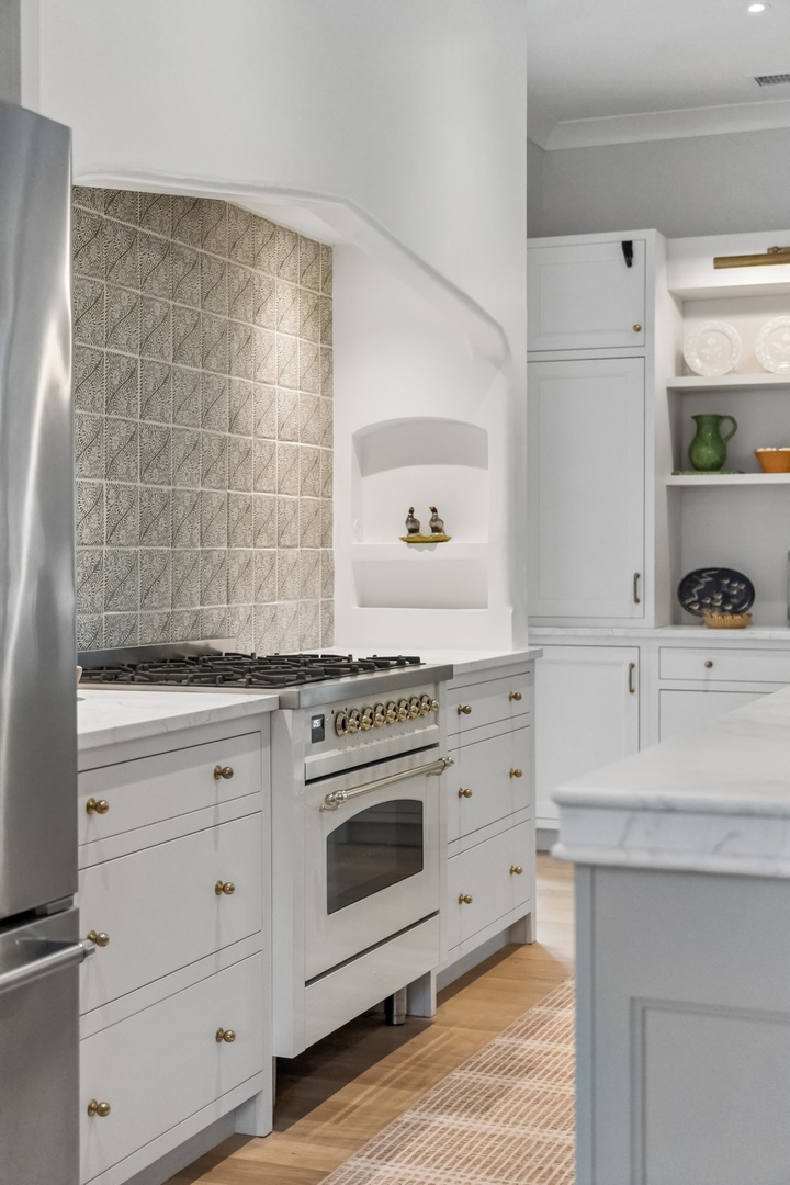Cook your favorite meals in this bright, well-appointed kitchen with a professional-grade gas range, elegant tile backsplash, and plenty of storage for all your culinary needs.