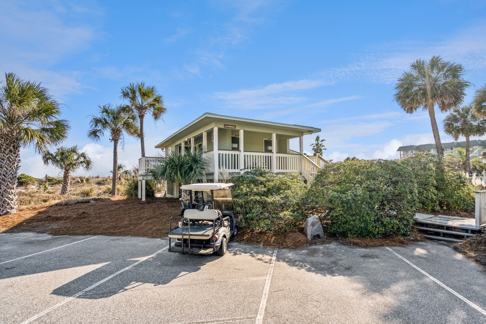 Charming coastal cottage with tropical palms and dedicated parking spaces in a peaceful island setting.