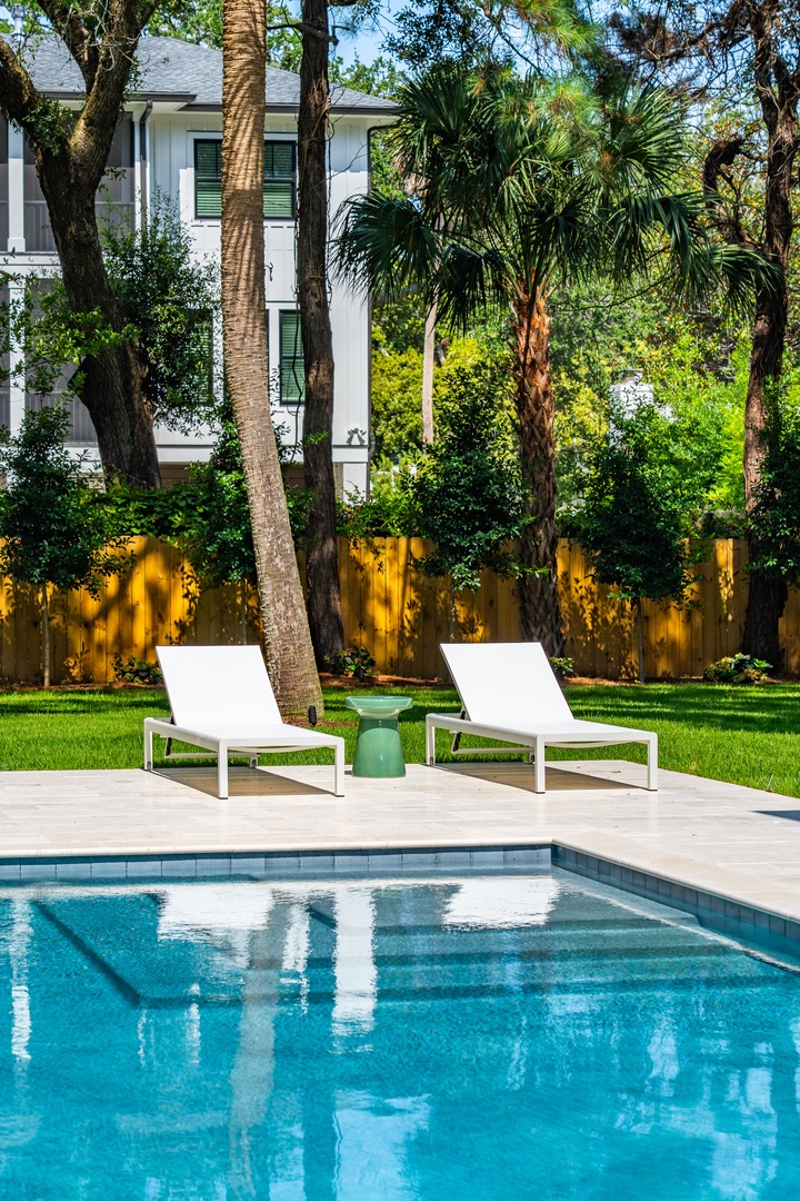 A private backyard oasis awaits you, with a sparkling pool framed by lush palms and tropical greenery. Stretch out on modern white loungers and soak up the Florida sunshine in complete serenity.