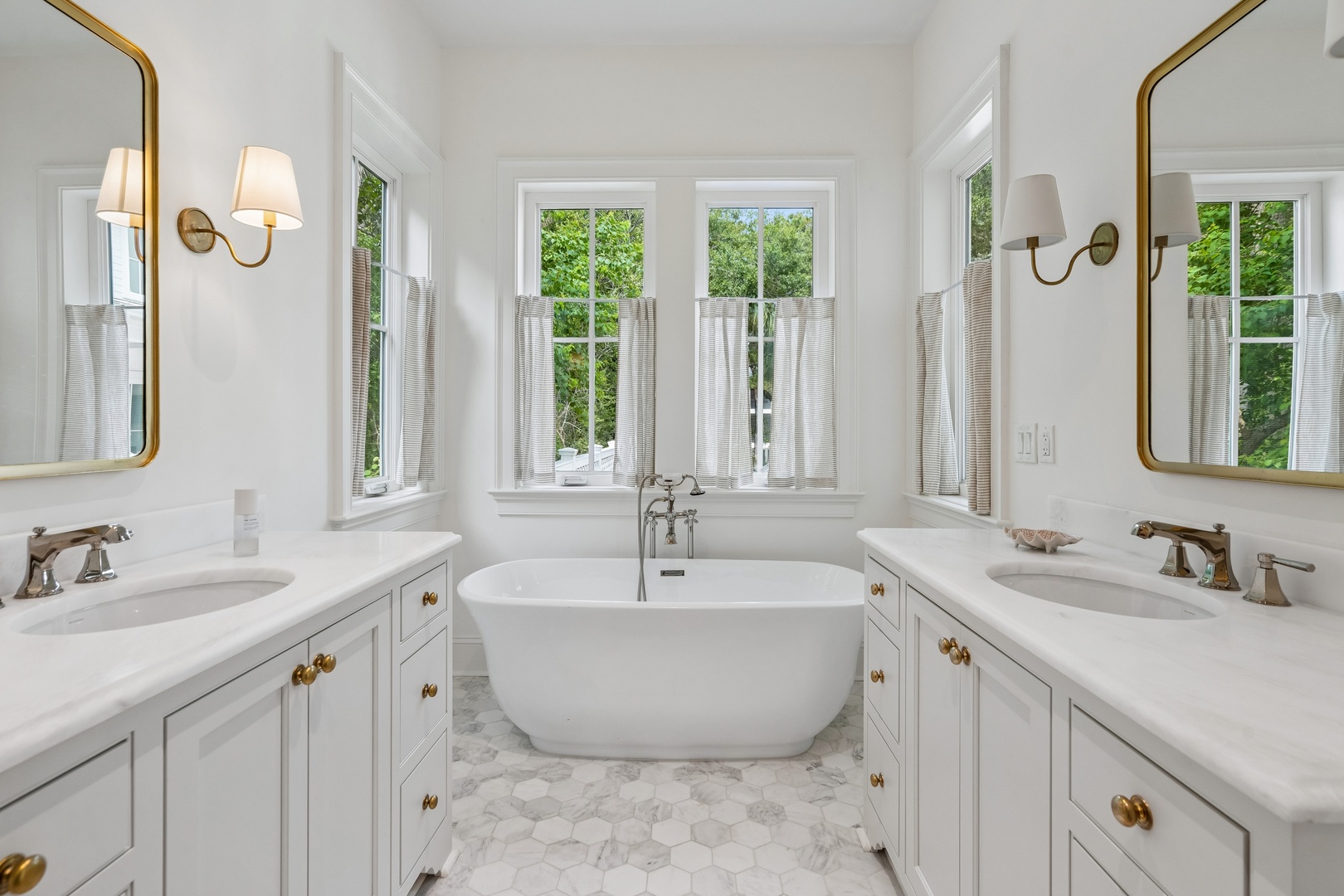 Your private spa-like retreat features a stunning freestanding soaking tub framed by windows that overlook lush greenery, with dual vanities offering plenty of space to unwind and prepare for your day.