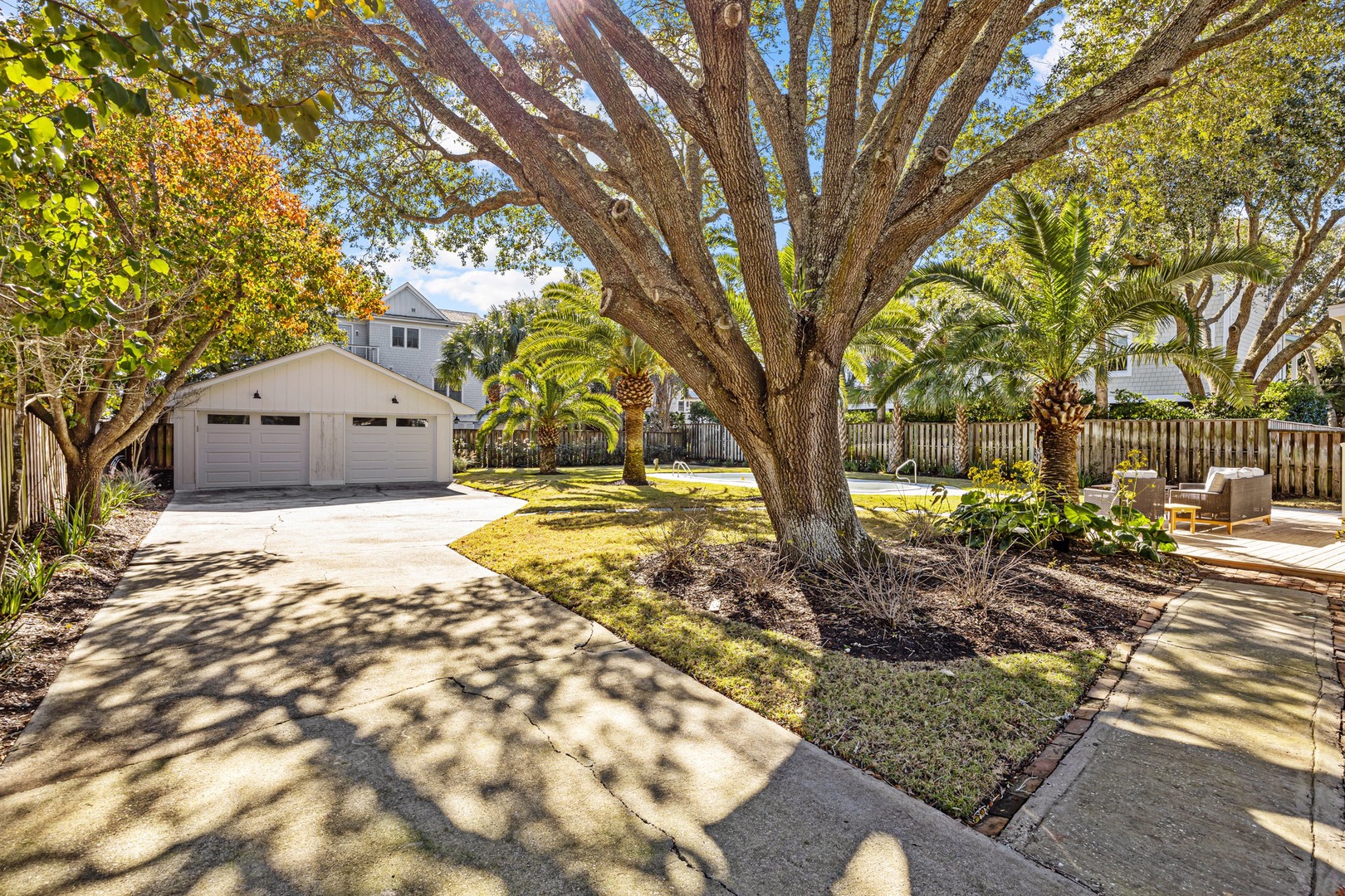 A peaceful residential property featuring mature landscaping, palm trees, and a spacious two-car garage in a quiet neighborhood setting.
