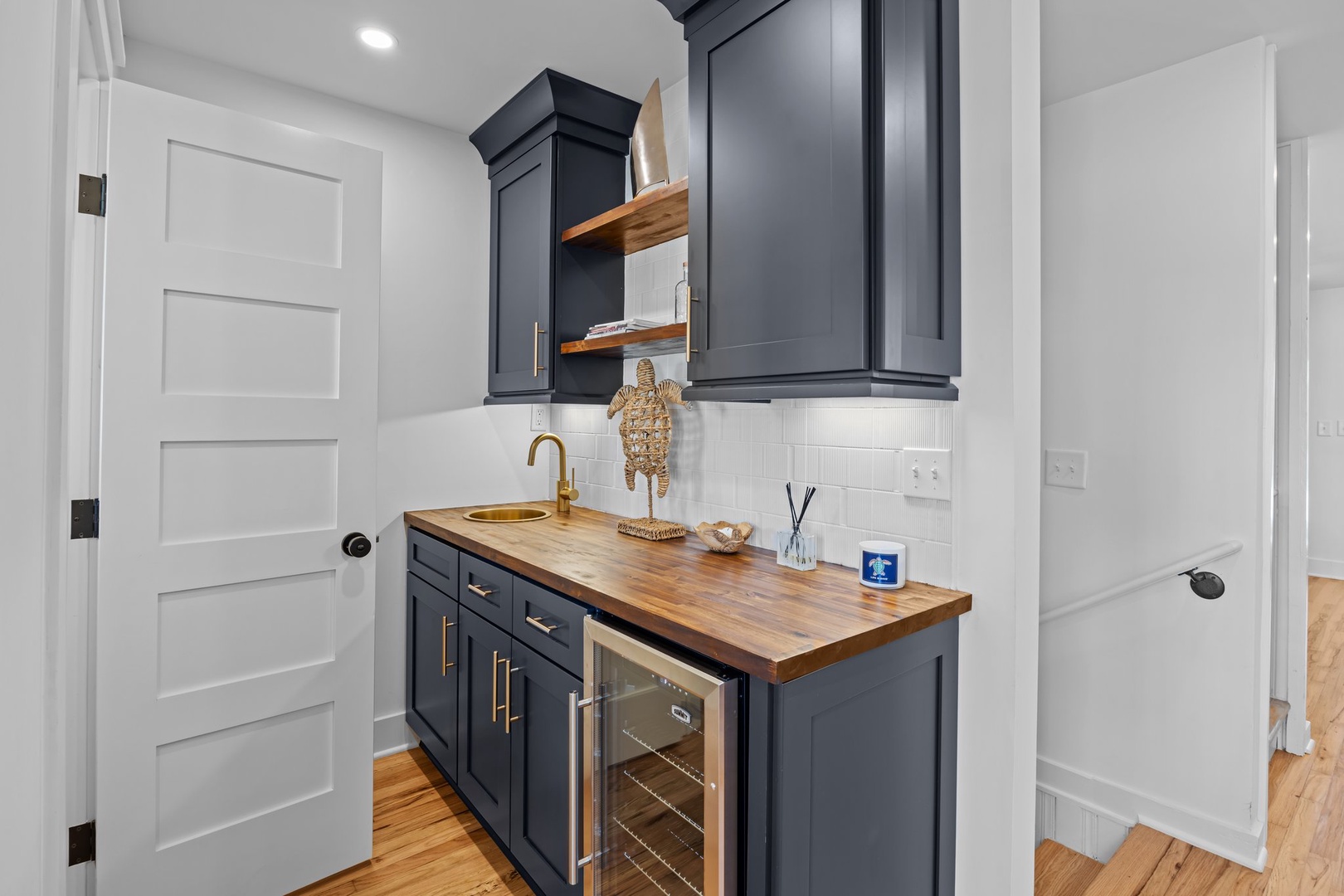 Your stylish wet bar awaits with rich navy cabinetry, warm wood counters, and brass fixtures for evening cocktails.