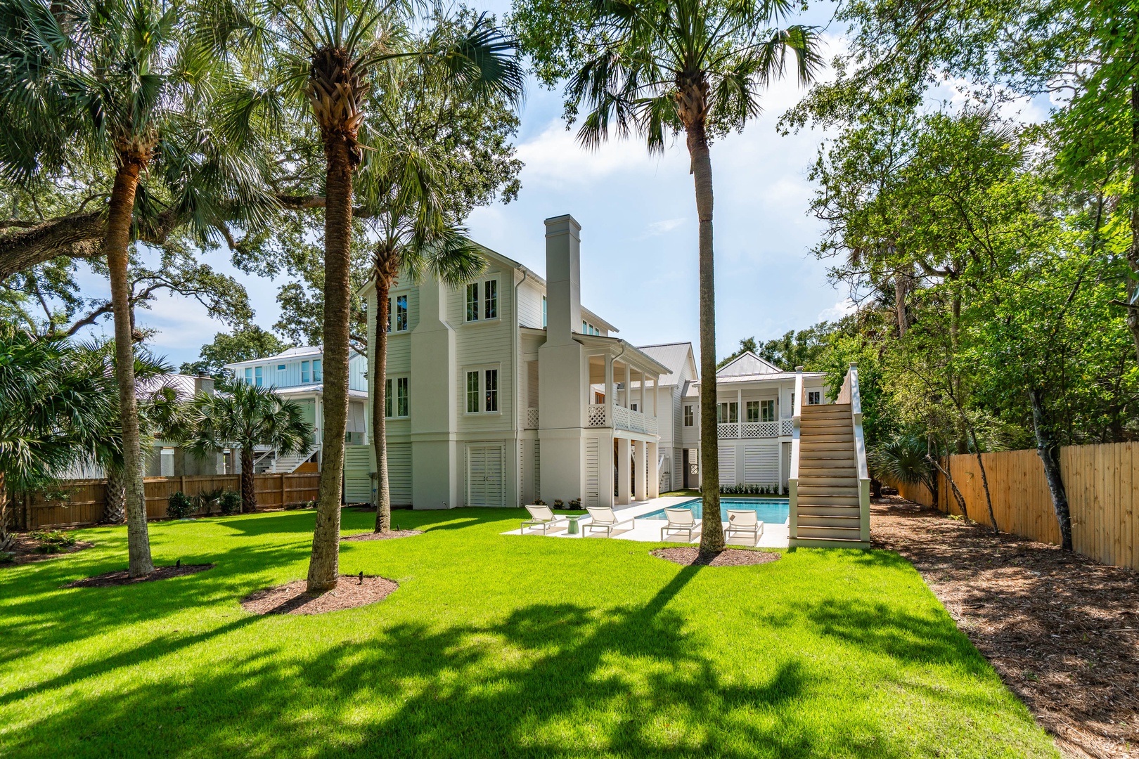 Elegant coastal retreat nestled among mature palms and lush greenery, featuring a private pool and expansive outdoor space perfect for sunny southern days.
