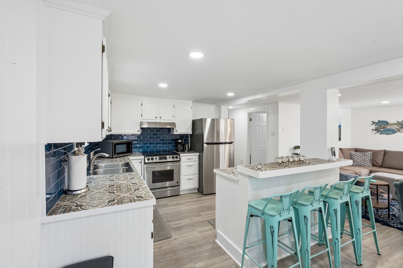 Your spacious kitchen features gleaming granite counters, stainless steel appliances, and charming turquoise bar stools perfect for morning coffee or casual dining.
