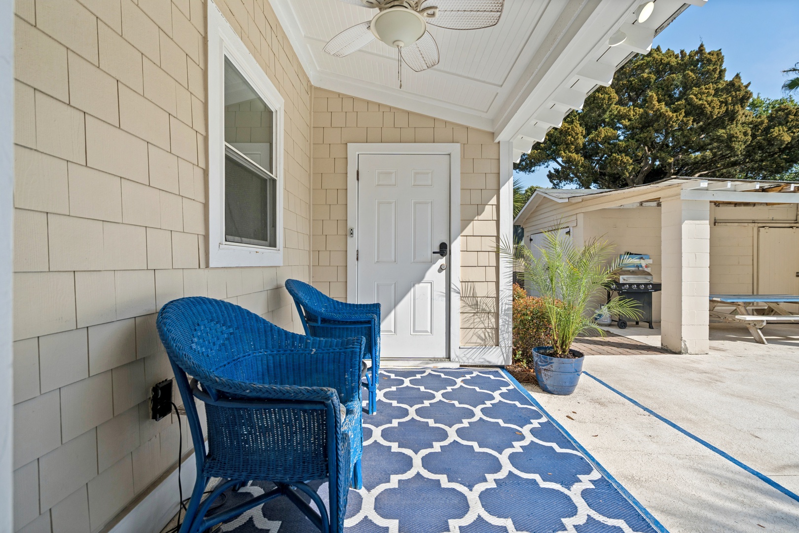 Relax in your private covered patio with stylish blue wicker seating and decorative rug—perfect for morning coffee or evening unwinding.