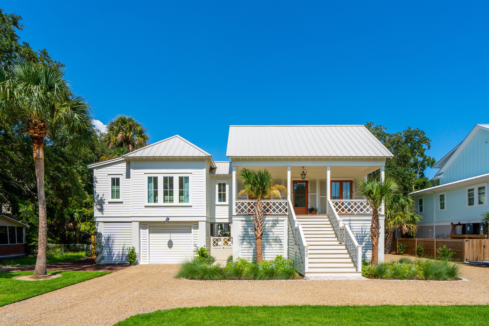 Charming coastal cottage with palm trees and a welcoming covered porch in a quiet residential neighborhood.