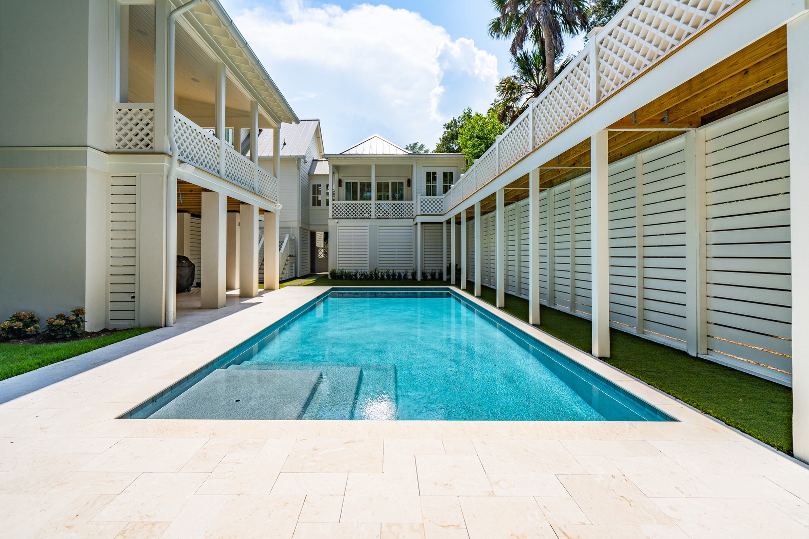 A private courtyard with a sparkling pool framed by elegant white architecture and tropical greenery—your own secluded retreat for sunny afternoons and refreshing swims.