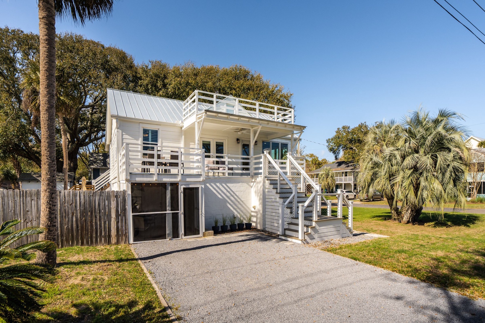 Modern coastal retreat with elevated deck and tropical landscaping in a peaceful neighborhood setting.