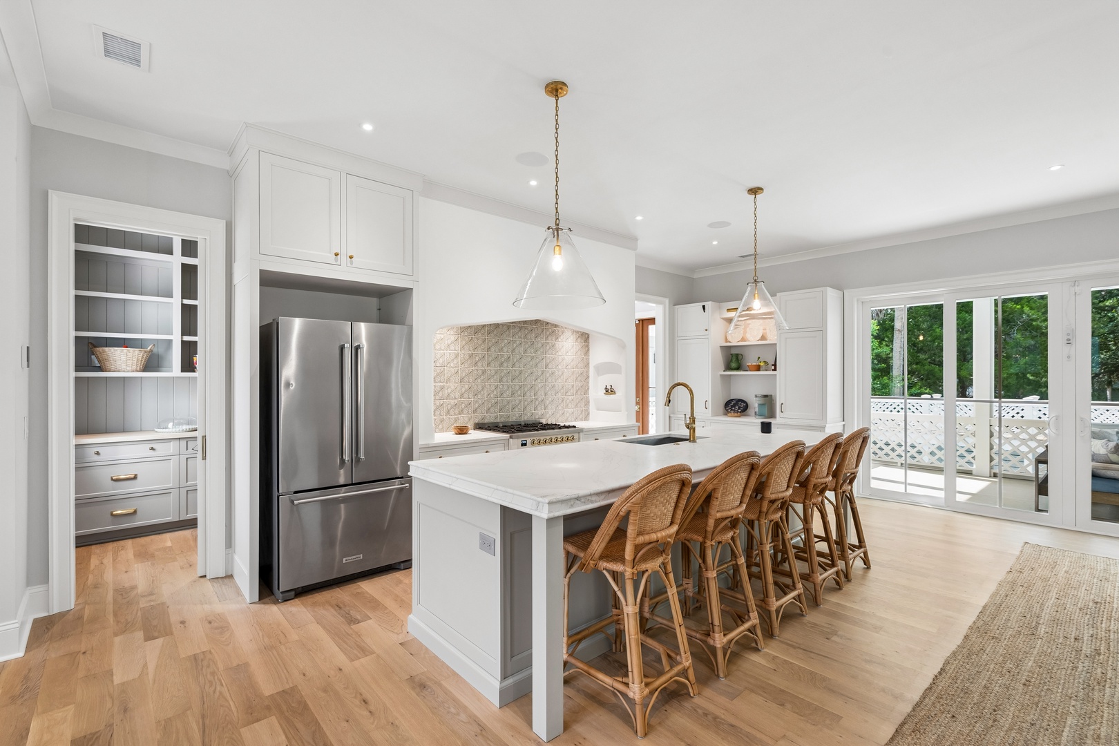 Gather with loved ones in your bright, airy kitchen featuring custom cabinetry, premium appliances, and a spacious island with seating for six. Large glass doors flood the space with natural light and open to your private outdoor retreat.