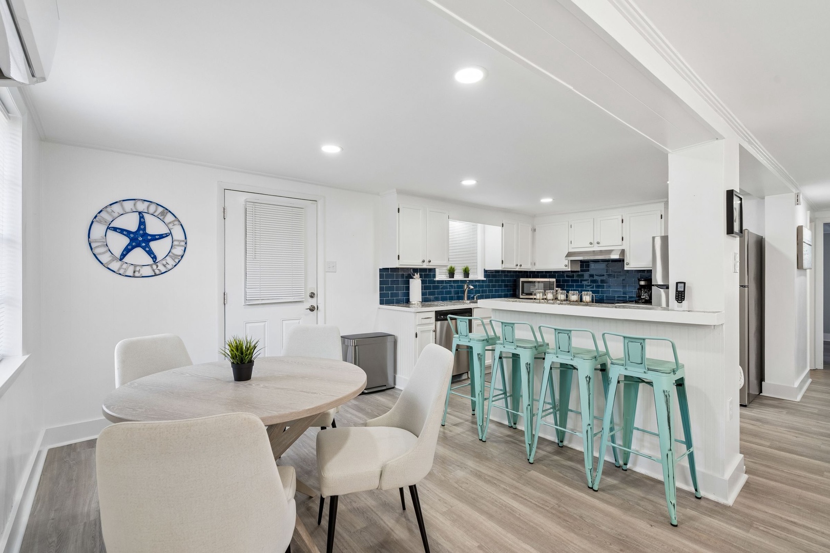 You'll love this bright open-plan space where crisp white cabinets meet cheerful turquoise bar stools and coastal charm.