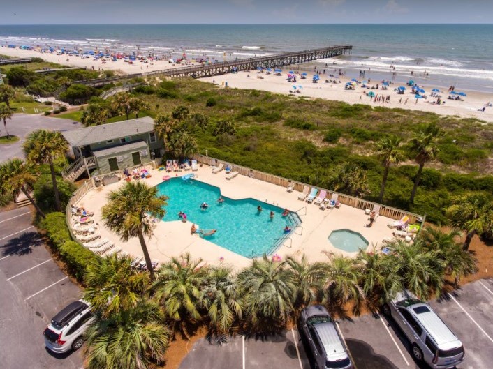 Beachfront property featuring a resort-style pool area with tropical landscaping, fishing pier, and direct beach access.