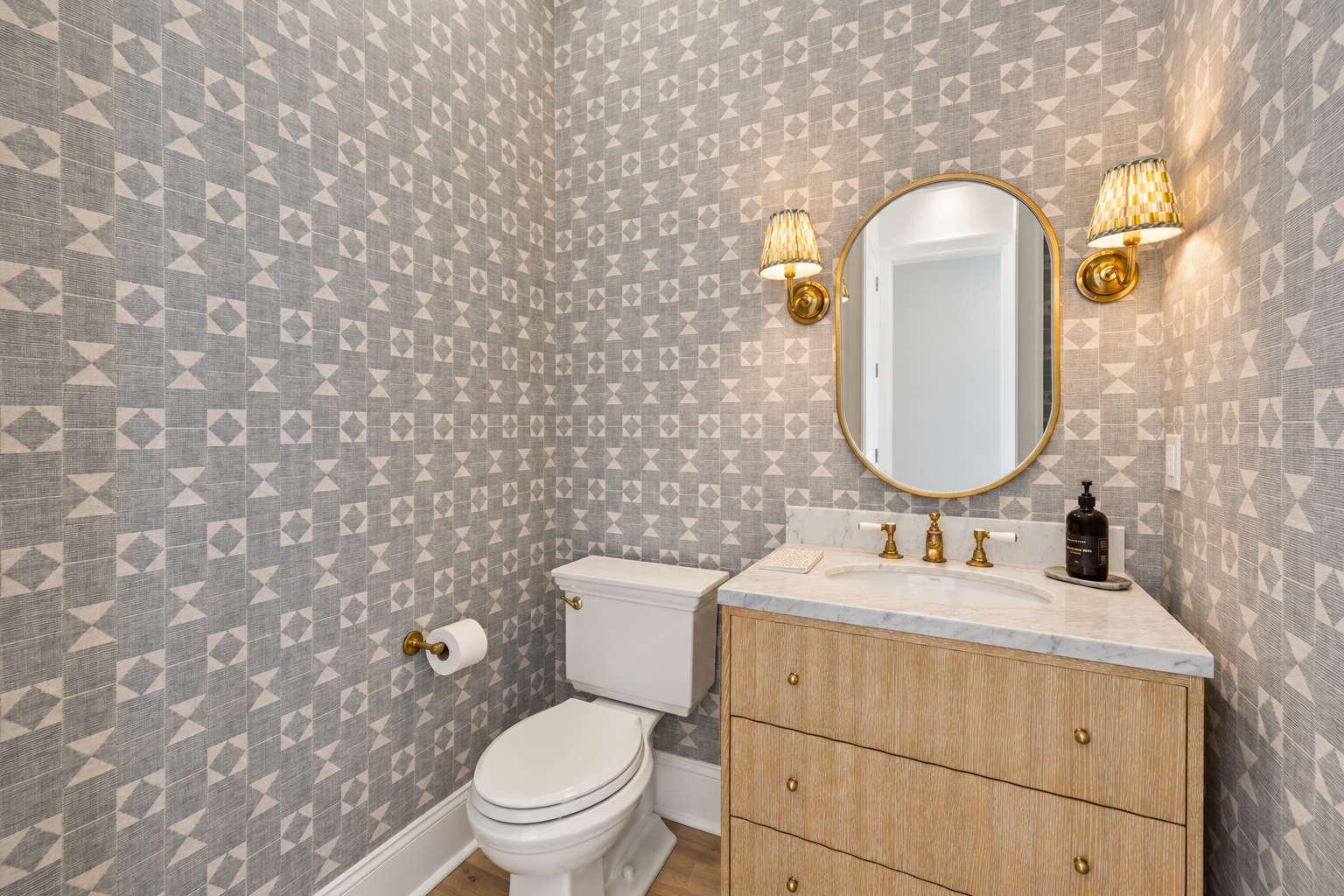 Refresh in this elegant powder room featuring geometric wallpaper and gleaming brass fixtures that add a touch of sophistication to your stay.