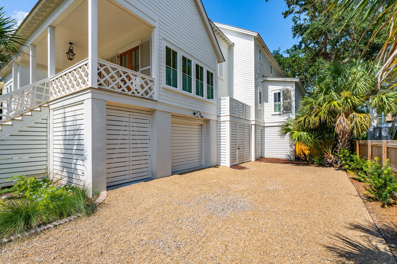 A charming coastal home with classic lattice-trimmed balconies and lush palm landscaping welcomes guests to a peaceful retreat under sunny skies.
