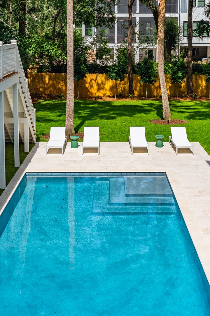 A serene oasis where lush tropical palms frame a sparkling pool and manicured lawn—perfect for unwinding under the warm sunshine.