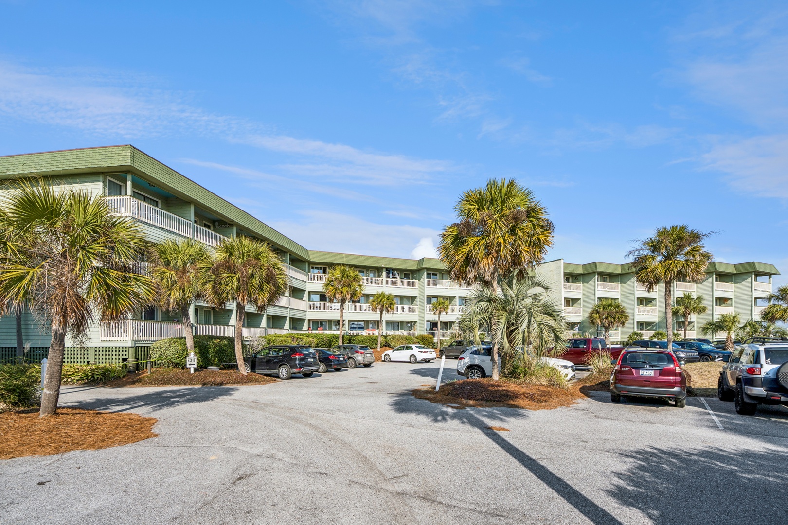 Coastal property featuring convenient parking surrounded by tropical palm trees under clear blue skies.