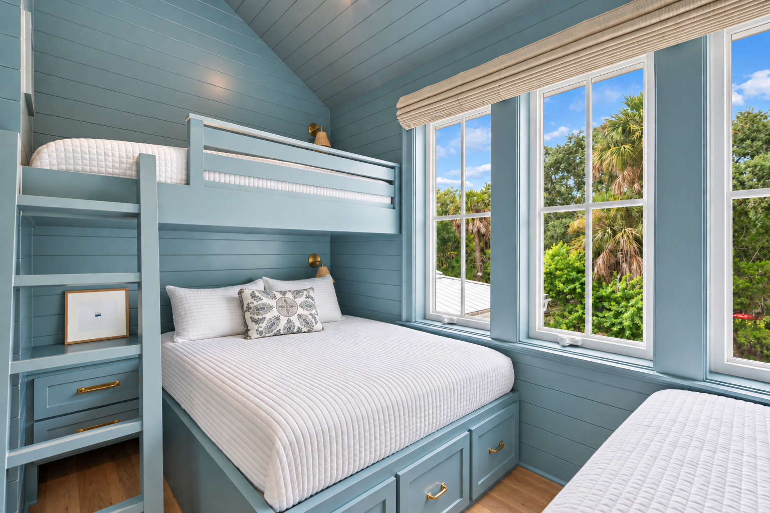 You'll love the coastal-inspired built-in bunk beds with crisp white linens, all bathed in natural light from large windows overlooking lush tropical greenery. Perfect for families or groups seeking comfort and style.