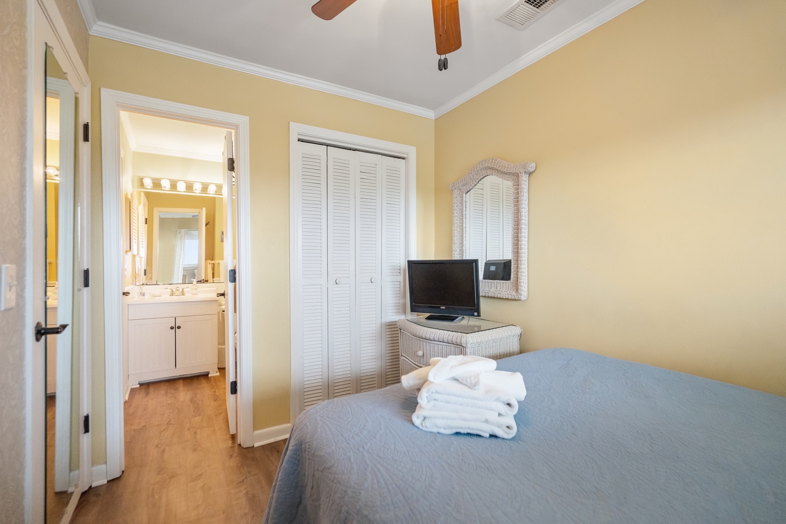Your serene bedroom features soft yellow walls, comfortable bedding, and an en-suite bathroom, creating the perfect peaceful retreat.