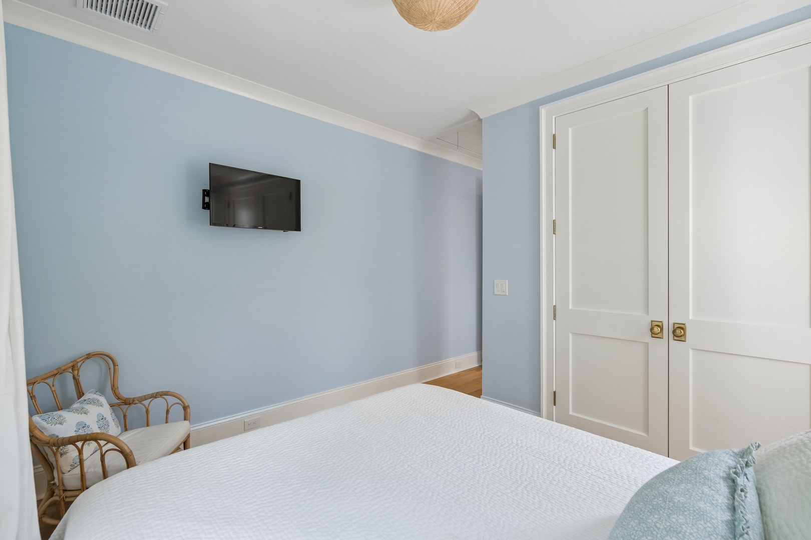 Unwind in your peaceful bedroom with soft blue walls, warm wood floors, and abundant storage. A cozy chair by the window invites you to relax with a book before slipping into your plush bed.