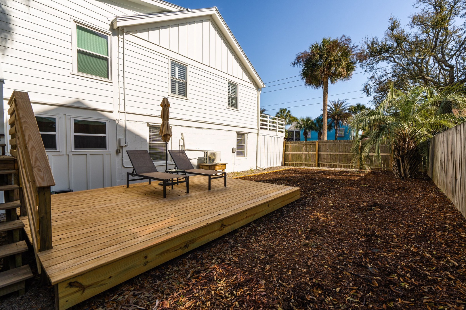 A charming coastal rental with wooden deck, tropical palms, and peaceful outdoor space for your perfect getaway.
