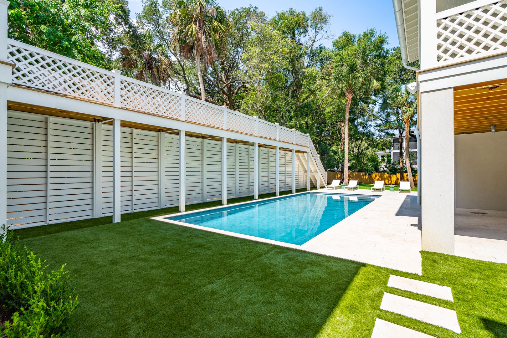 Step out to your private backyard retreat where a sparkling lap pool awaits, framed by lush greenery and sunny lounge chairs—perfect for peaceful mornings or afternoon swims.