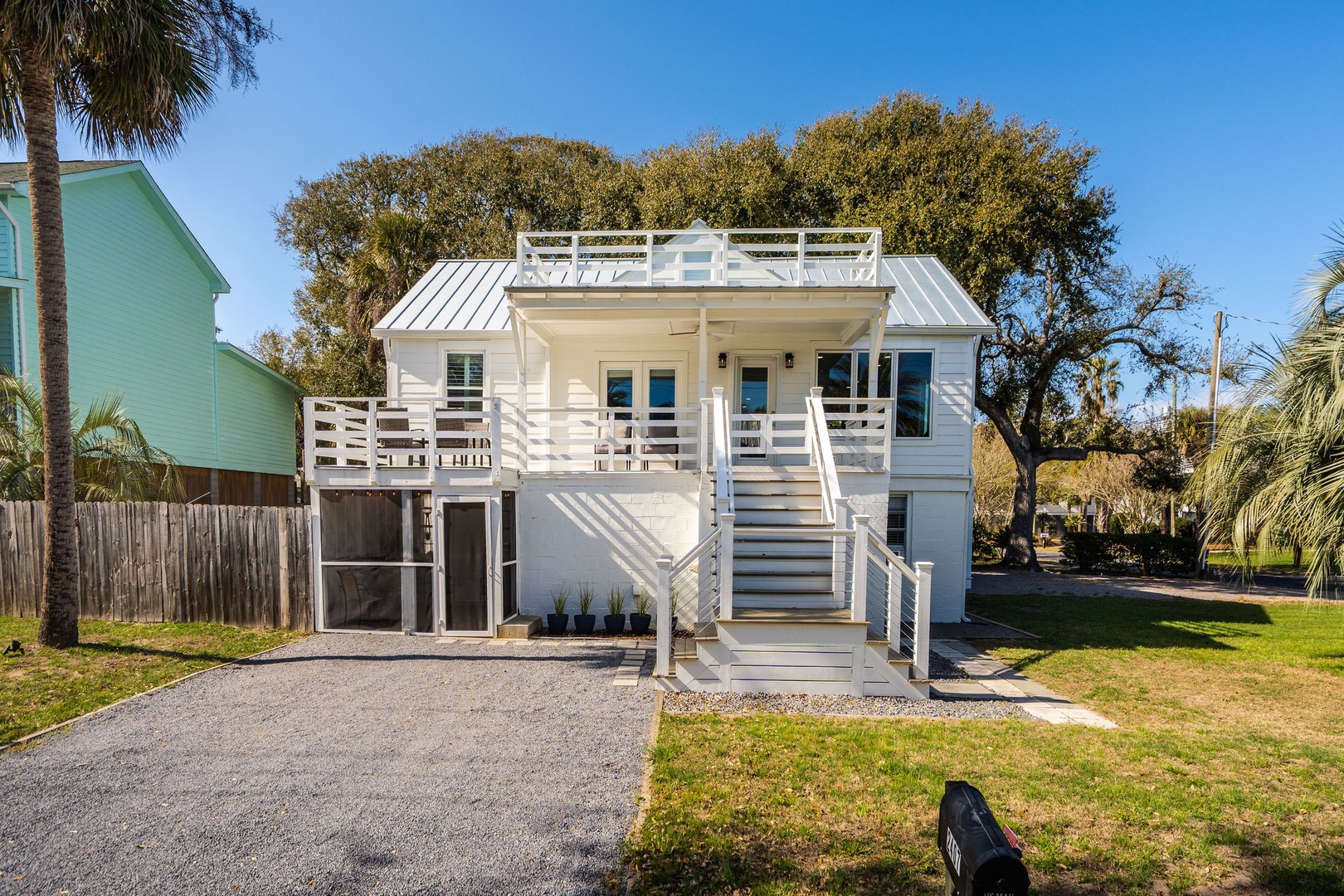 Modern coastal cottage with elevated design, rooftop deck, and tropical palm surroundings in a quiet residential setting.