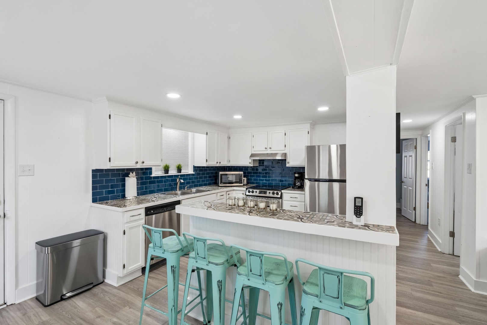 Cook and gather around your stylish kitchen island with modern appliances, blue subway tile backsplash, and cheerful turquoise seating for memorable meals.