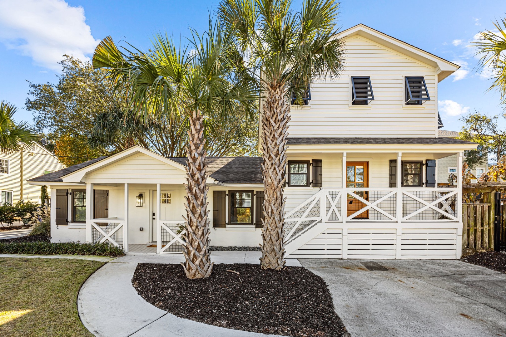 Charming coastal home with palm trees and white railings welcomes guests to a peaceful neighborhood setting.