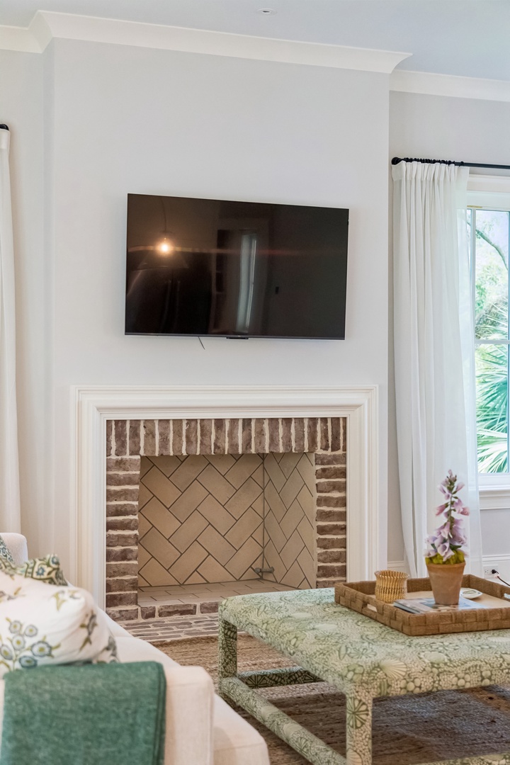 Settle into a cozy living room where you can unwind by the brick fireplace after exploring the area. Natural light filters through the windows, inviting you to relax on plush seating and enjoy your favorite shows.