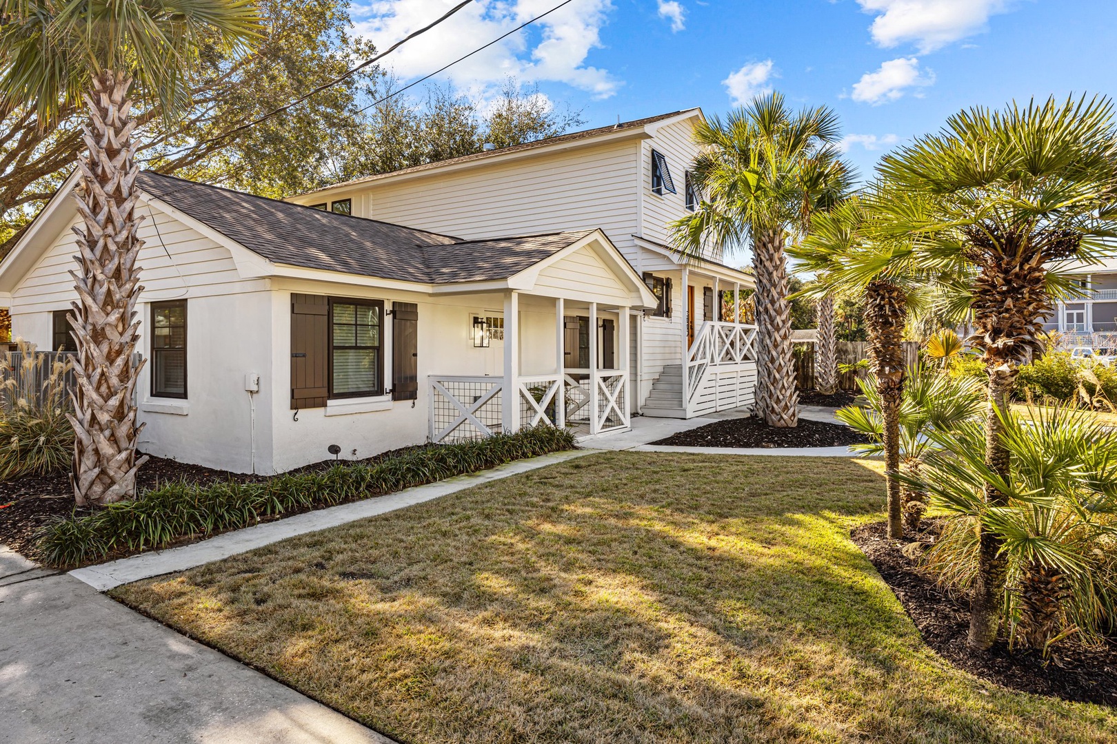 Charming coastal cottage with tropical landscaping and welcoming front porch in a peaceful neighborhood setting.