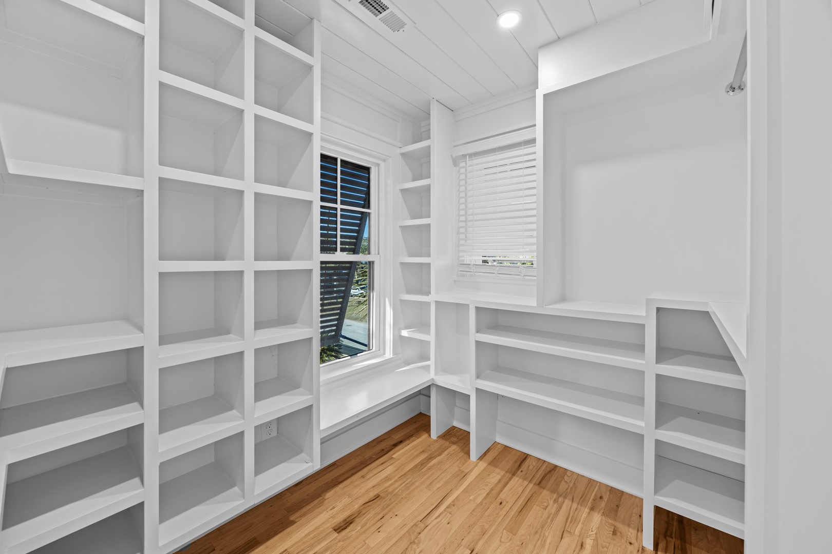 Your spacious walk-in closet features floor-to-ceiling shelving and warm hardwood floors for organized, luxurious storage.