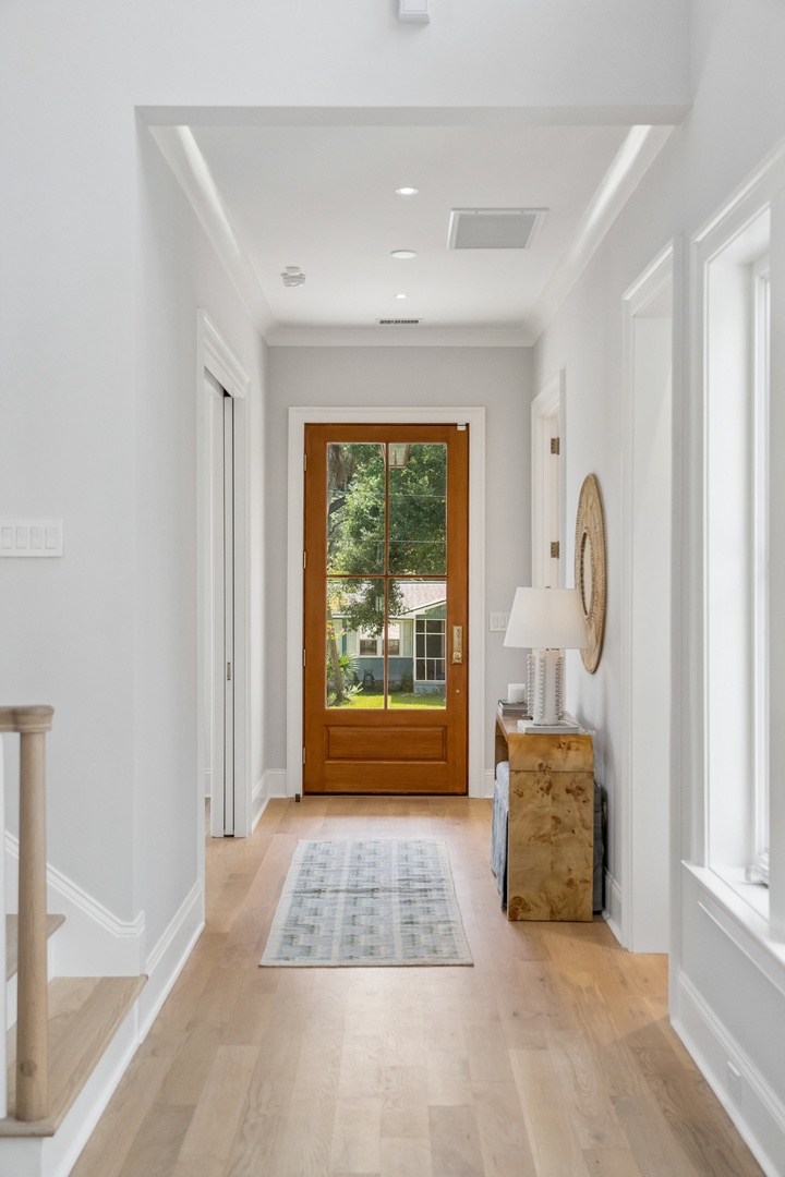 Step into your bright, welcoming entrance where natural light pours through the glass-paned door. Clean white walls and warm wood floors create an inviting first impression that feels like home.