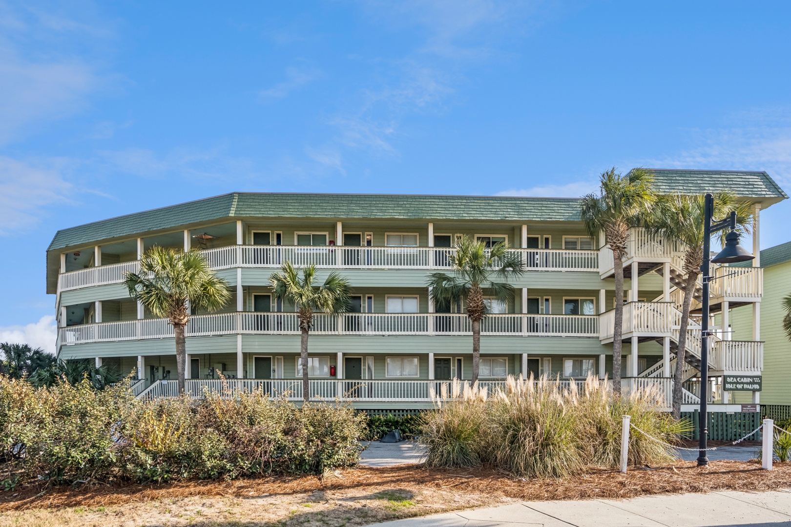 Coastal property featuring three levels of comfortable accommodations with spacious balconies and tropical palm landscaping.
