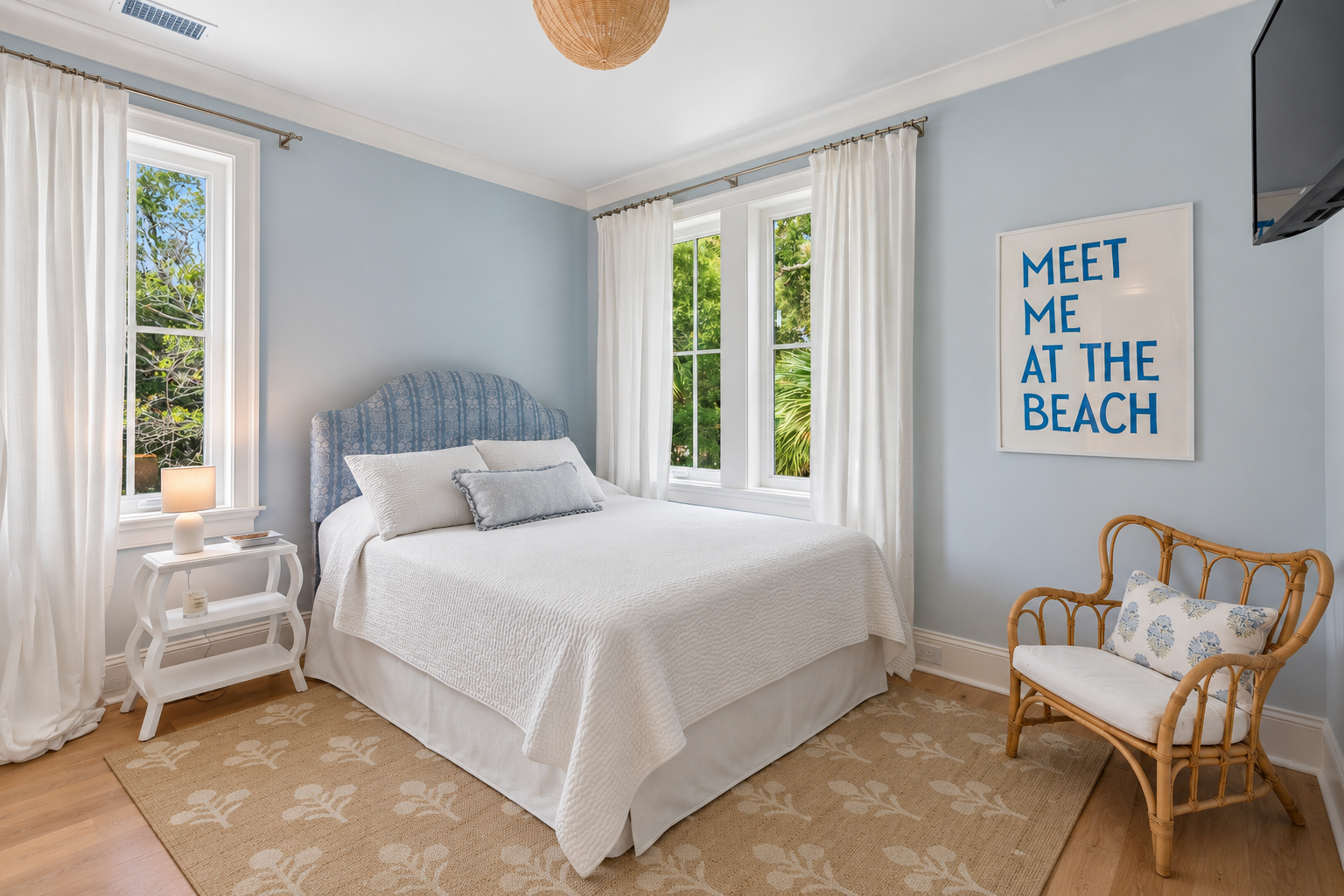 Drift off in this tranquil bedroom with crisp linens, a plush upholstered headboard, and bright windows that invite natural light. The coastal charm and cozy seating area make it your perfect retreat.
