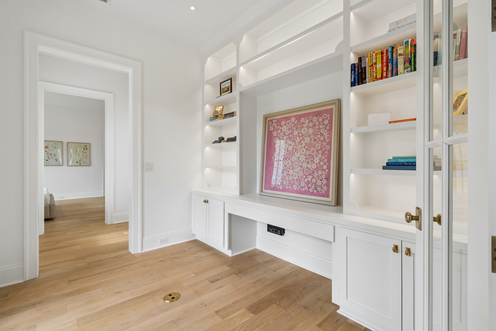 A thoughtfully designed space with built-in shelving and soft lighting invites you to unwind. Warm wood floors and pristine white millwork create an elegant retreat for reading or relaxation.