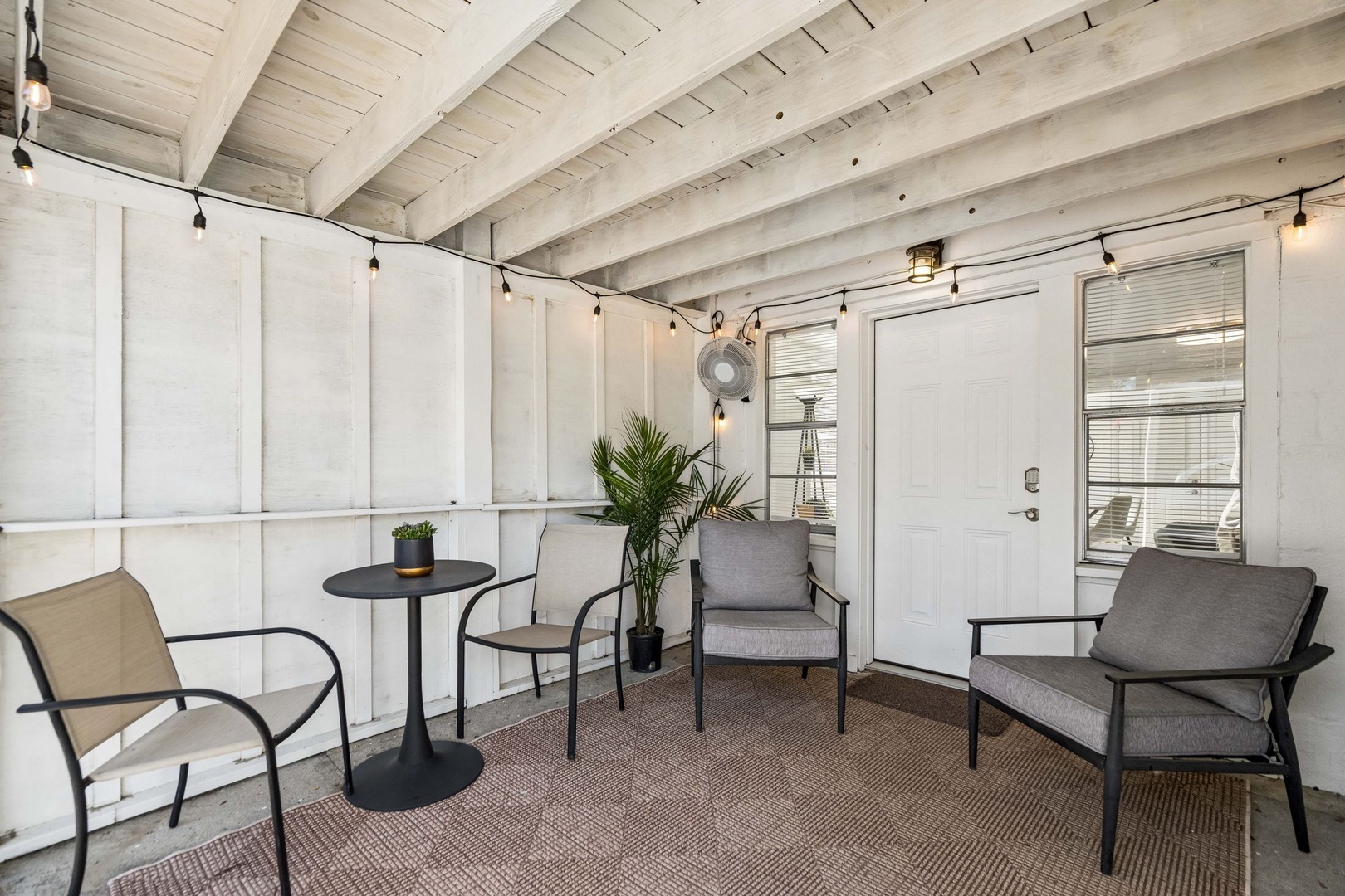 Your private covered patio offers a serene retreat with modern seating and twinkling string lights overhead.