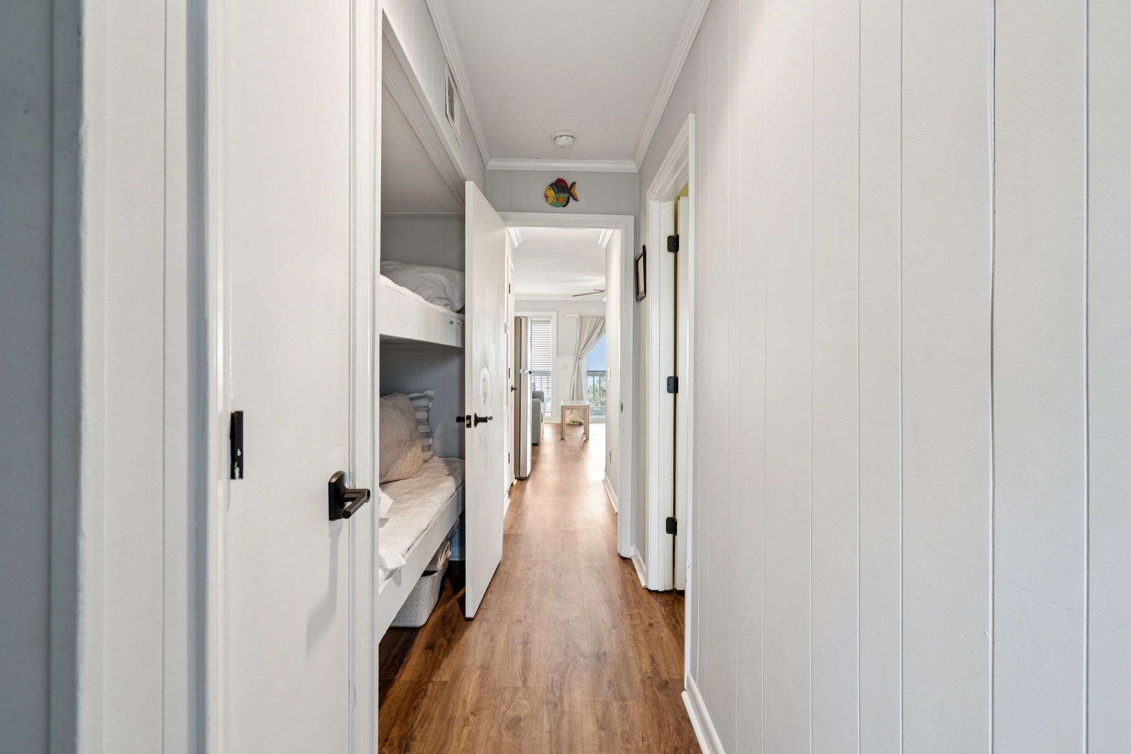 Your private hallway connects cozy bunk beds to bright living spaces, with warm wood floors guiding you home.