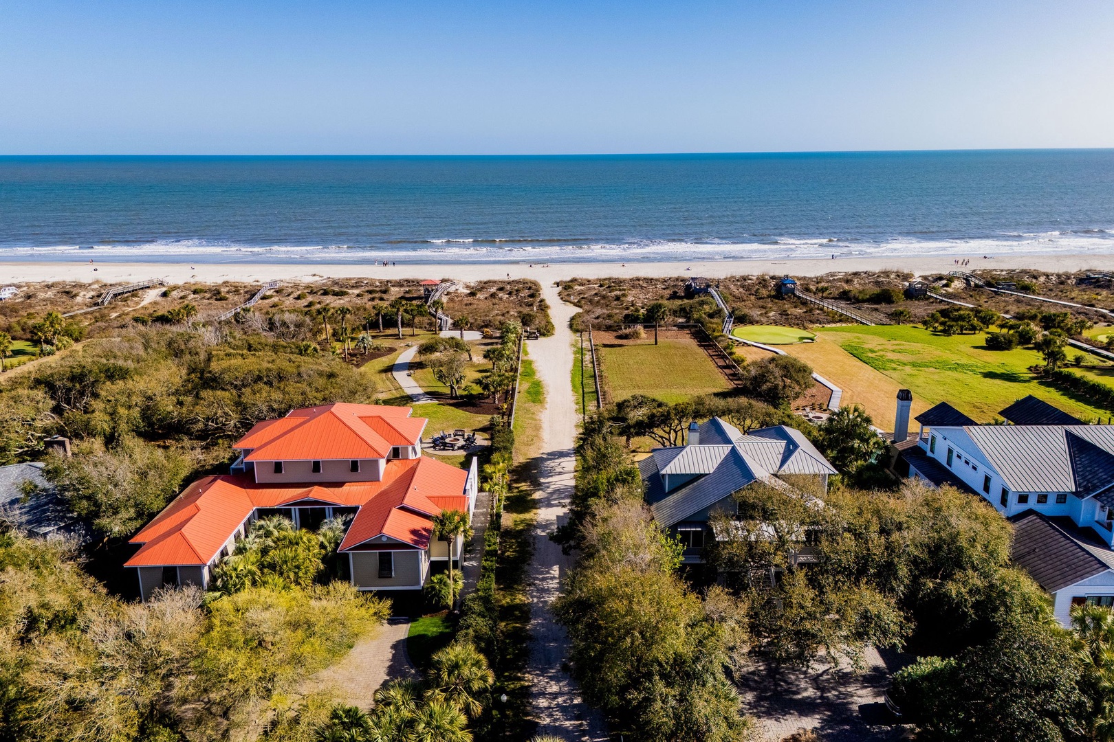 Coastal properties nestled between lush vegetation and pristine beach, offering direct access to sandy shores and ocean waves.