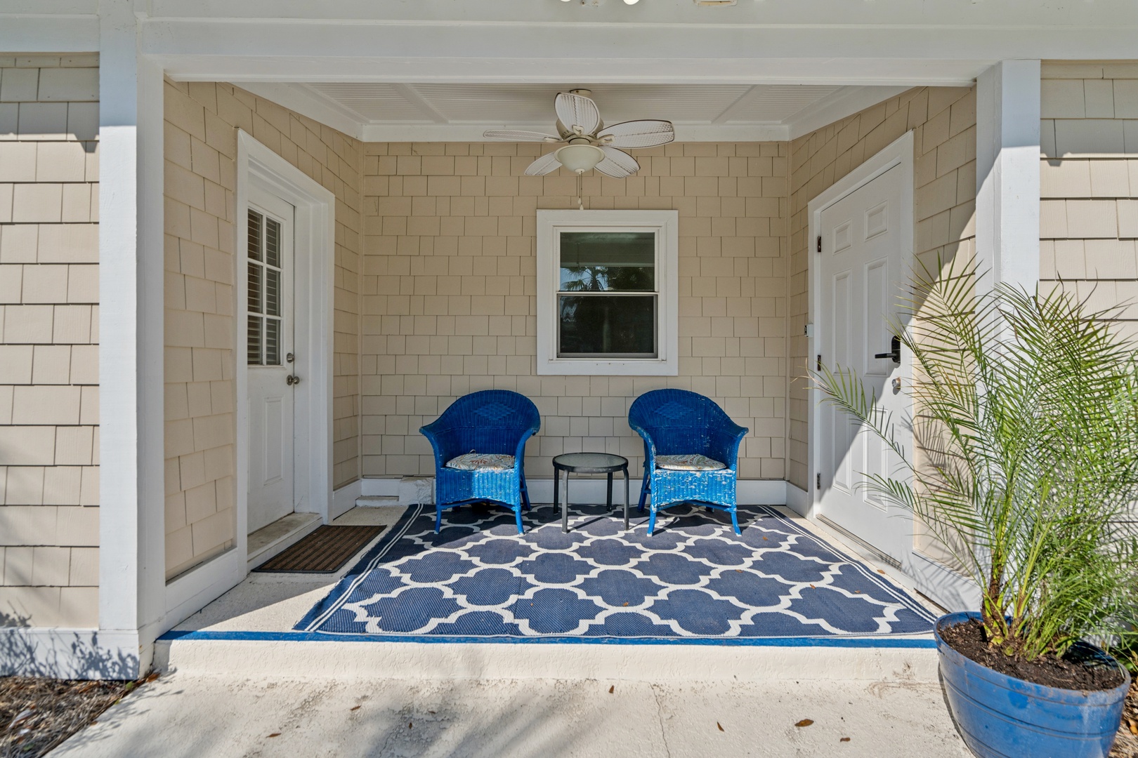 Relax in your private covered patio with comfortable blue chairs and tropical palm accents, perfect for morning coffee or evening conversations.