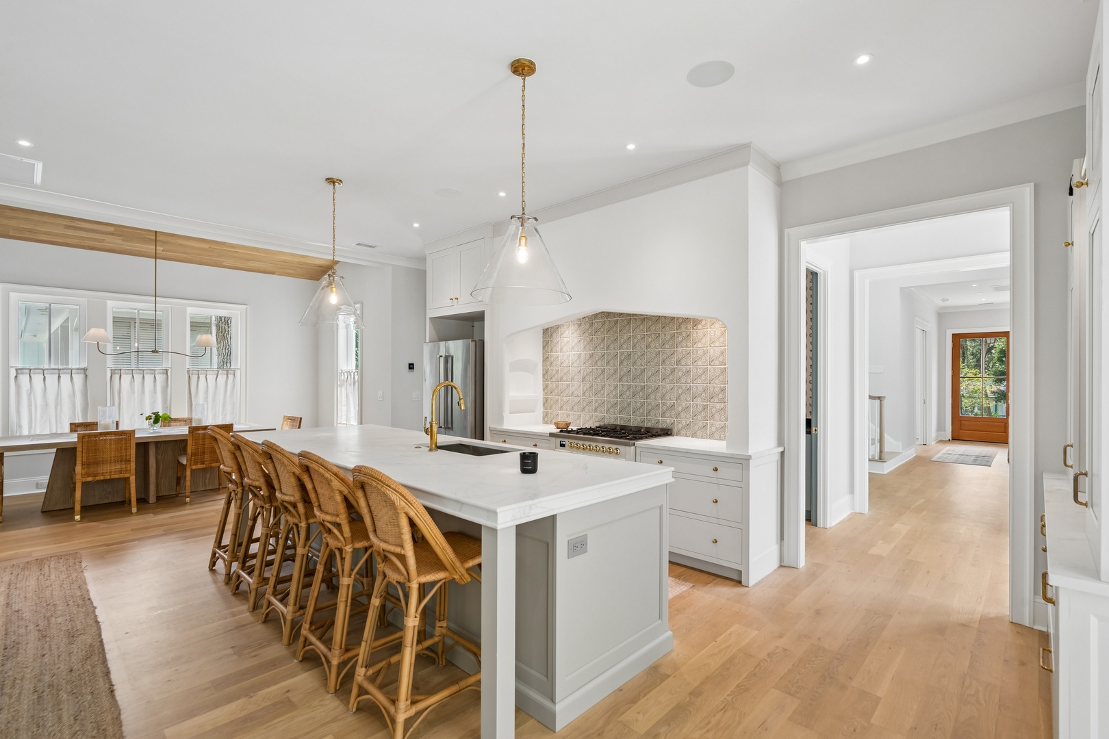 Gather in your spacious kitchen with a gleaming marble island, elegant pendant lights, and warm wood barstools perfect for morning coffee or evening cocktails.