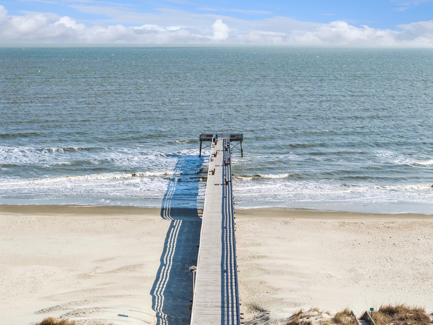 Scenic coastal location with a wooden pier extending into ocean waters, offering nearby beach access for seaside relaxation.