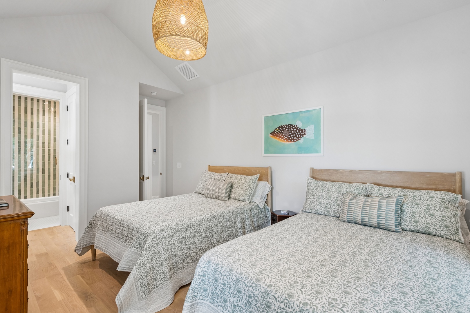 Settle into this tranquil bedroom where two comfortable beds await beneath coastal-inspired decor and a charming woven pendant light. The soothing palette and natural textures invite peaceful rest after your adventures.