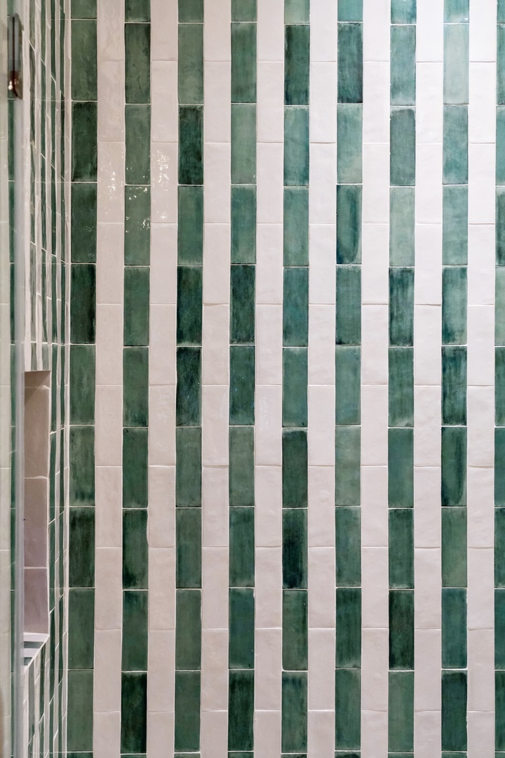 A close-up view of the property's striking architectural facade, featuring elegant vertical striping in green and white tiles that create a distinctive visual pattern.
