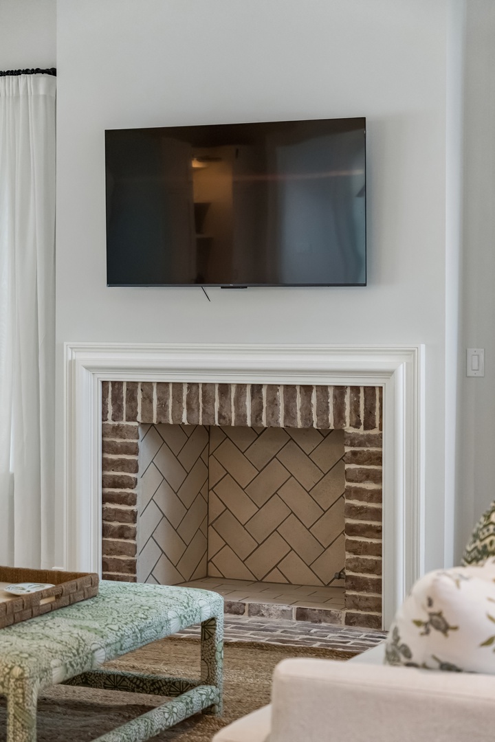Settle into your cozy living space, where a charming brick fireplace with herringbone tiling creates a warm focal point. Soft seating and natural light make this the perfect spot to unwind.